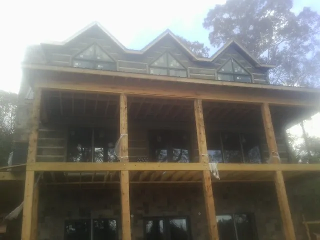 Dormers and porch framing on a large log home under construction — Roof Coating work by our crew in Abbeville