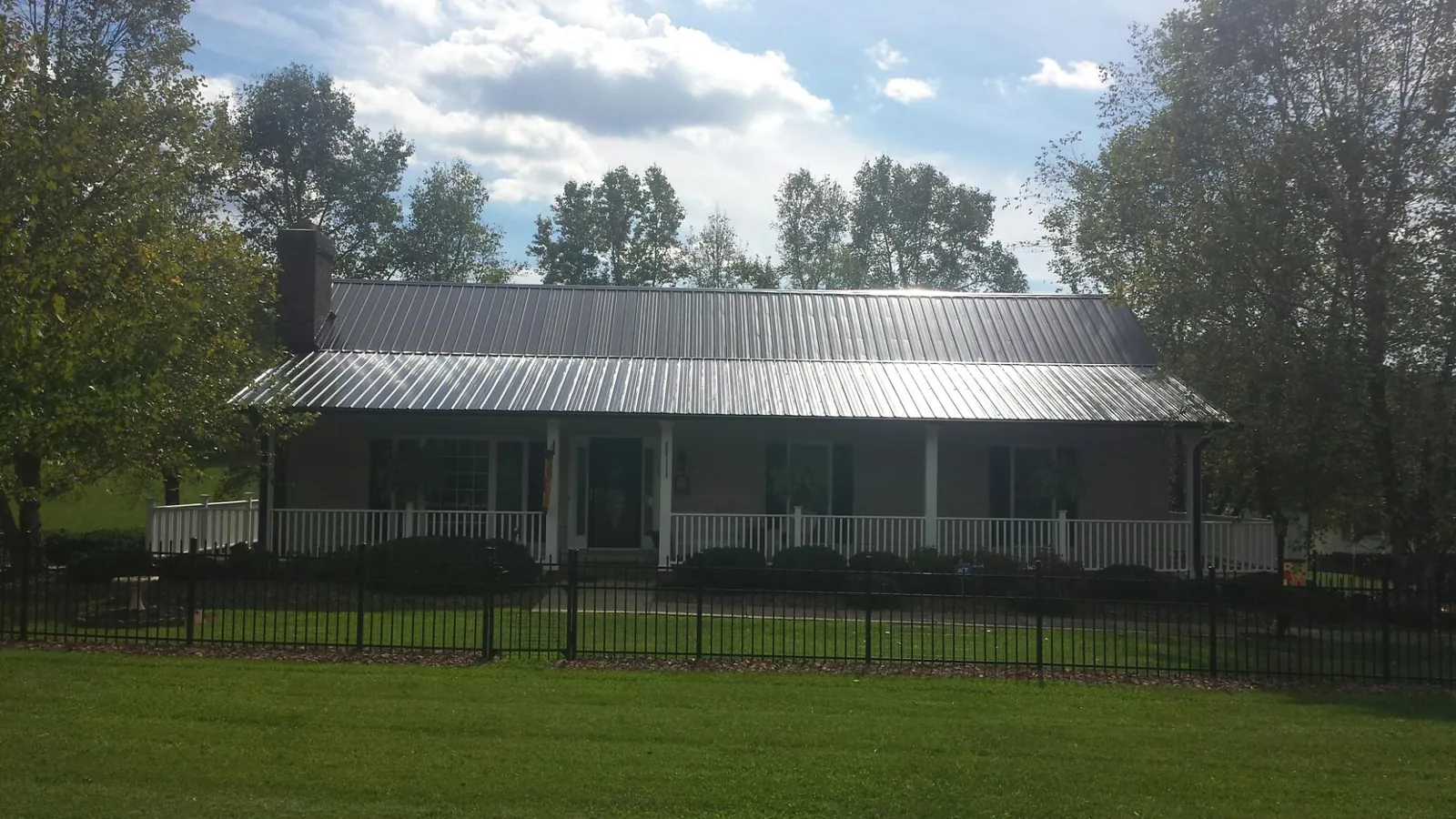 Gray metal roof on a brick ranch with a full width front porch — Gutter Guard Installation work by our crew in Abbeville