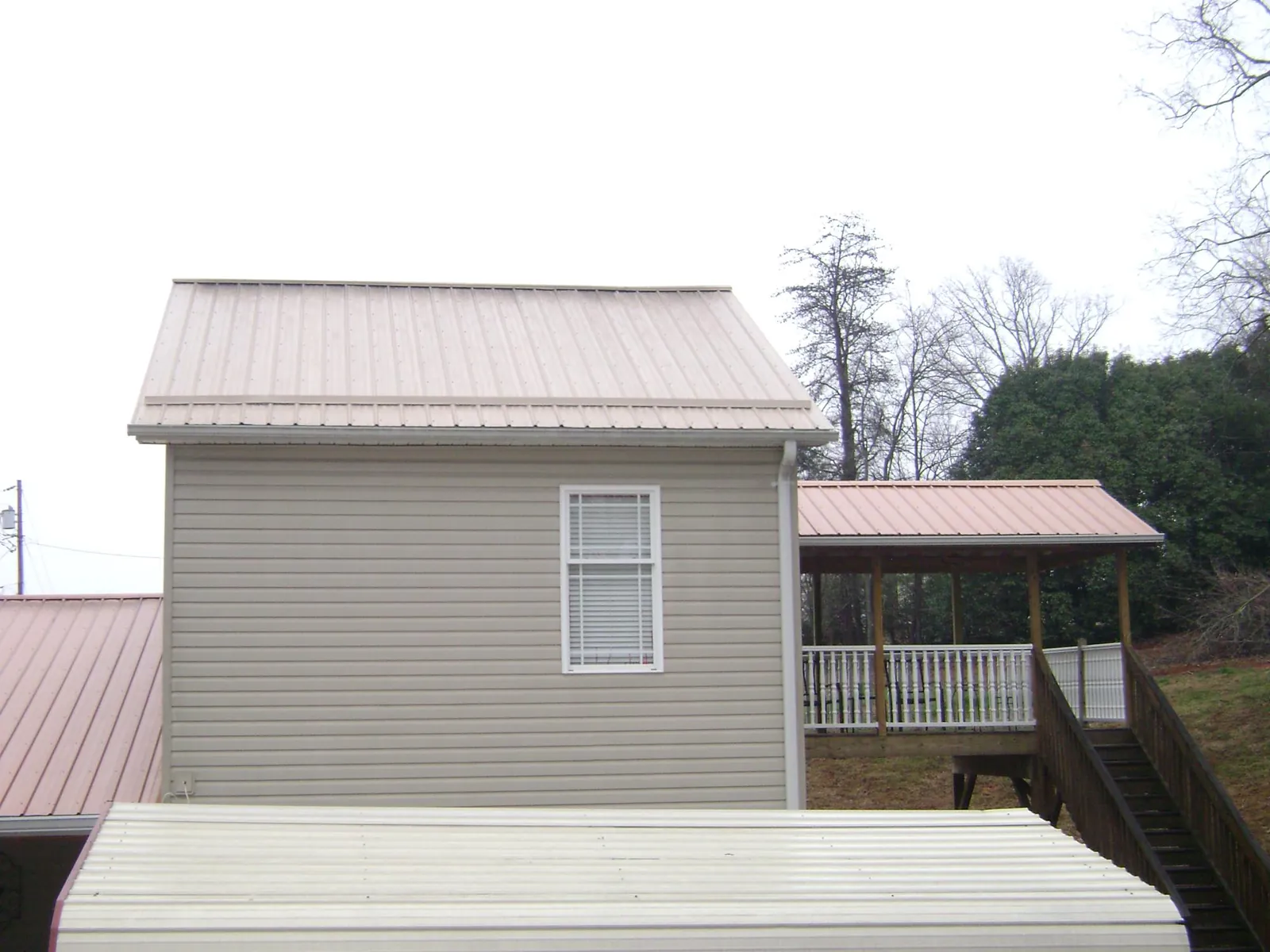 Tan metal roofs on a two story addition and attached porch, from a Roof Replacement job in Abbeville